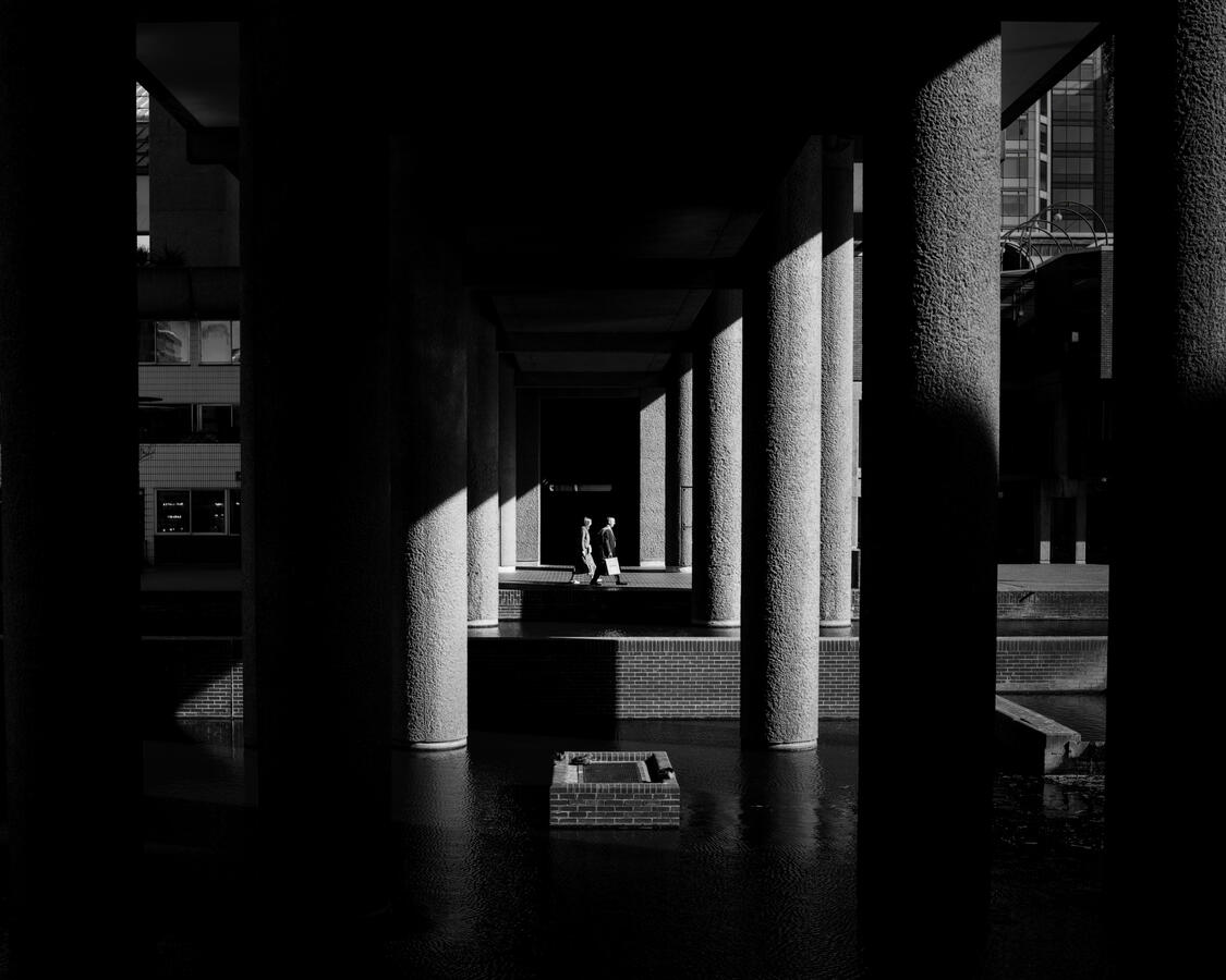 Light and shadows in the Barbican London lighting up a couple as they walk through