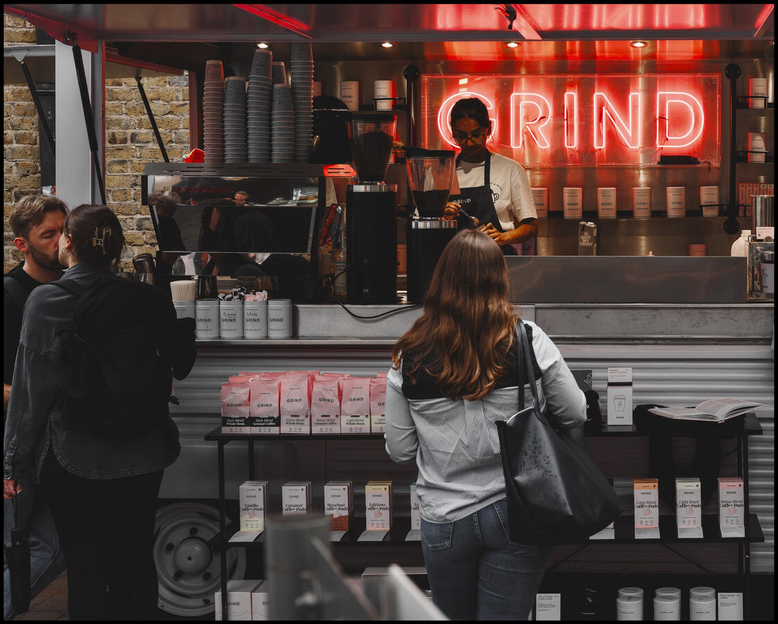 Photo of a couple kissing whilst waiting to order coffees