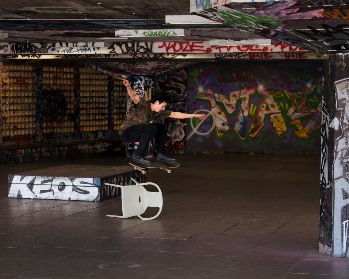 Skateboarder caught mid air jumping over a chair