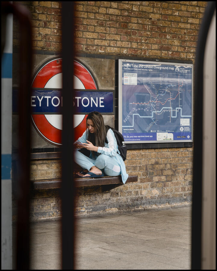 Lady sitting cross legged on station bench