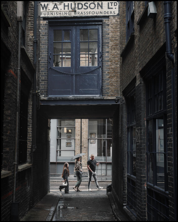 3 persons walking past an alleyway entrance
