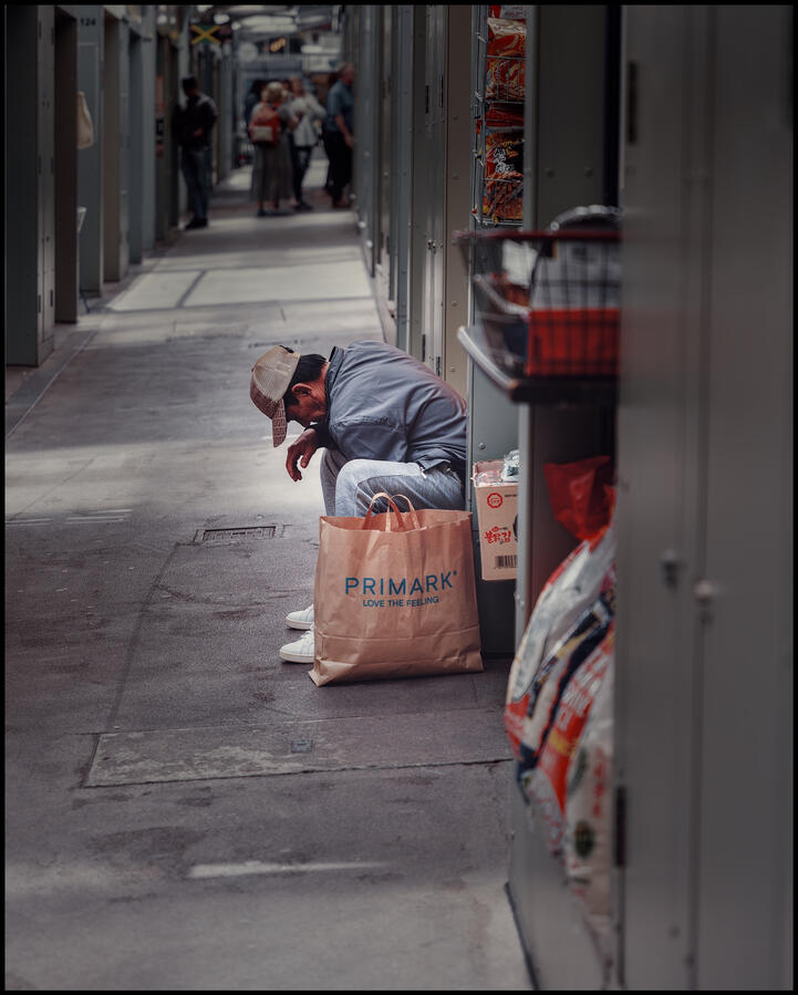 Photo of a Man seated with bag of shopping from Primark